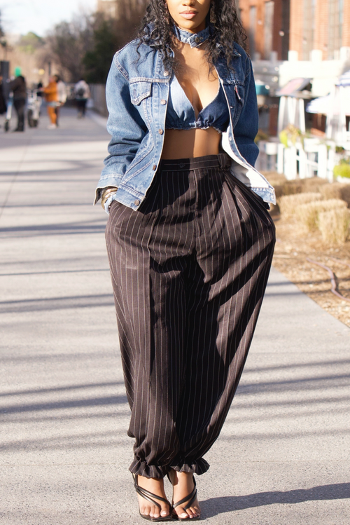 A woman in black pinstripe joggers and a denim jacket.