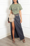Woman in a graphic t-shirt and upcycled fashion wrap skirt with taupe fur belt purse and heeled sandals.