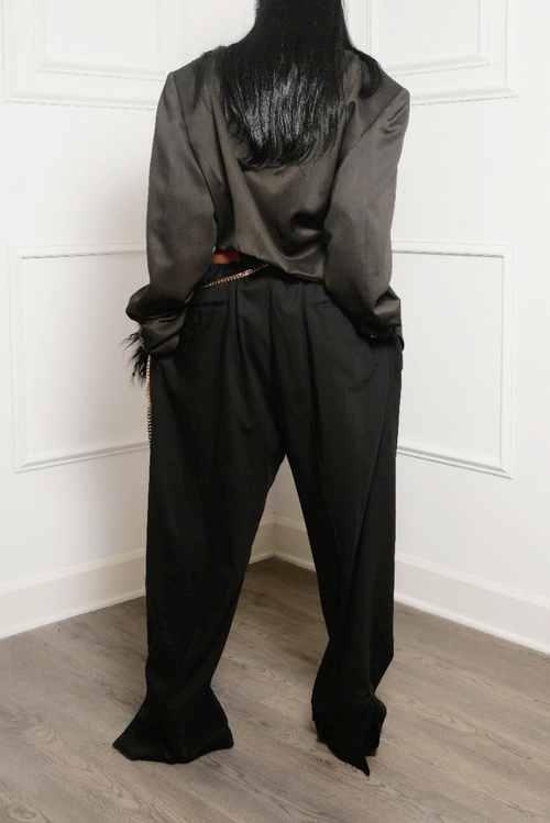 The back of a woman wearing black side split slacks and a black jacket.