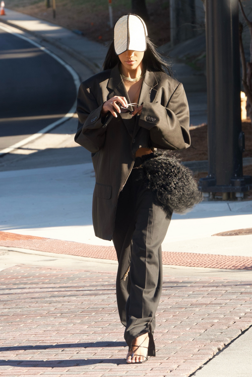A stylish woman in a straw hat and black pants strutting confidently down the street.