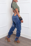 A woman wearing upcycled jeans and strappy heels posing sideways to the camera.