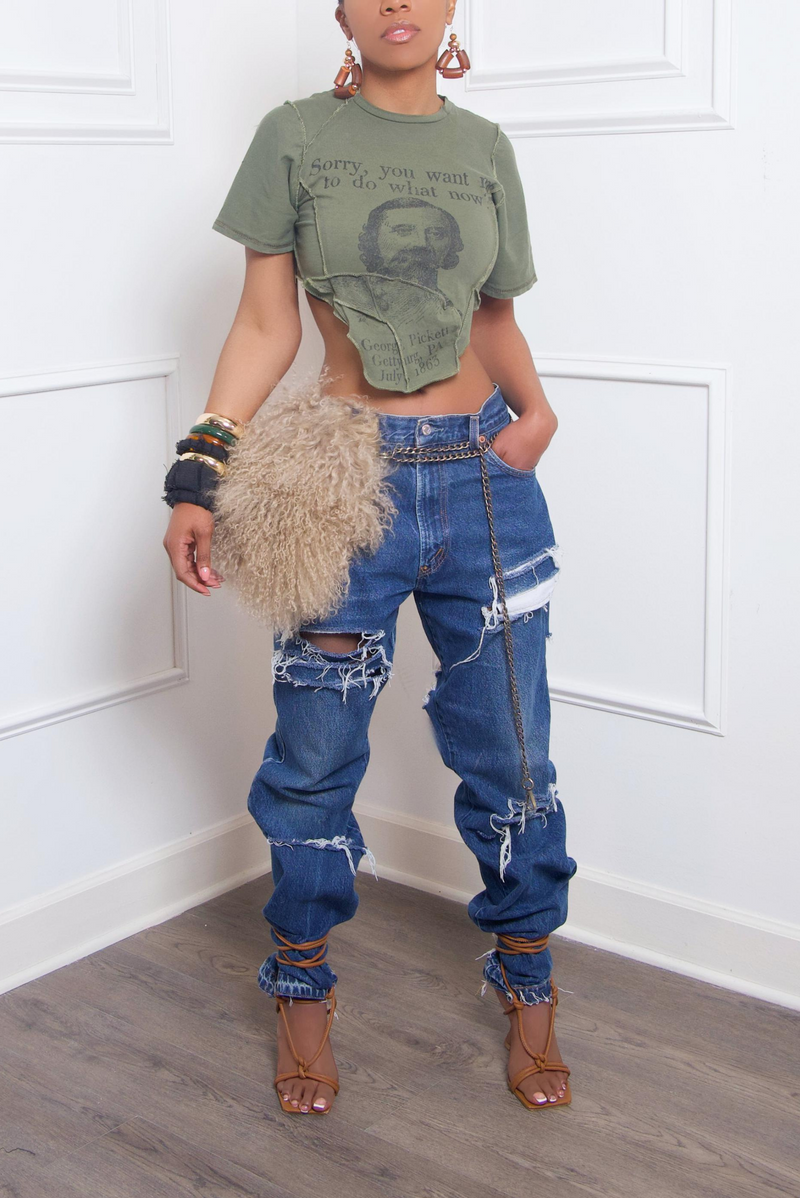 A woman posing in a cropped graphic tee, upcycled jeans heavily distressed, and strappy heels, accessorized with statement jewelry.