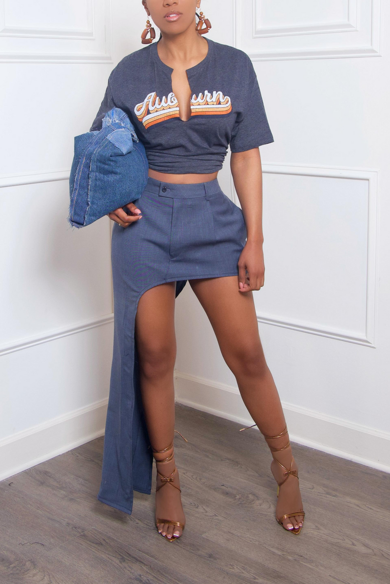 A woman holding an upcycled denim bag and posing in a cropped t-shirt, high-waist shorts, and strappy sandals.