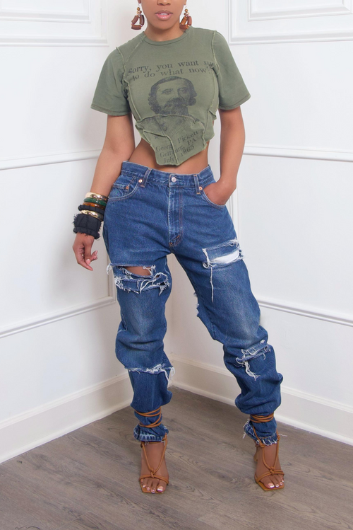 Woman in a cropped olive t-shirt and upcycled denim jeans with brown strappy heels.
