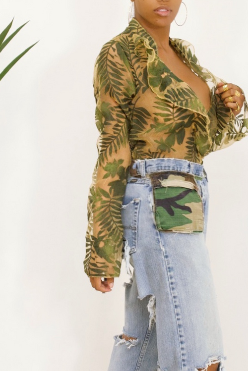 A woman wearing camouflage ripped jeans and a tactical camouflage top.